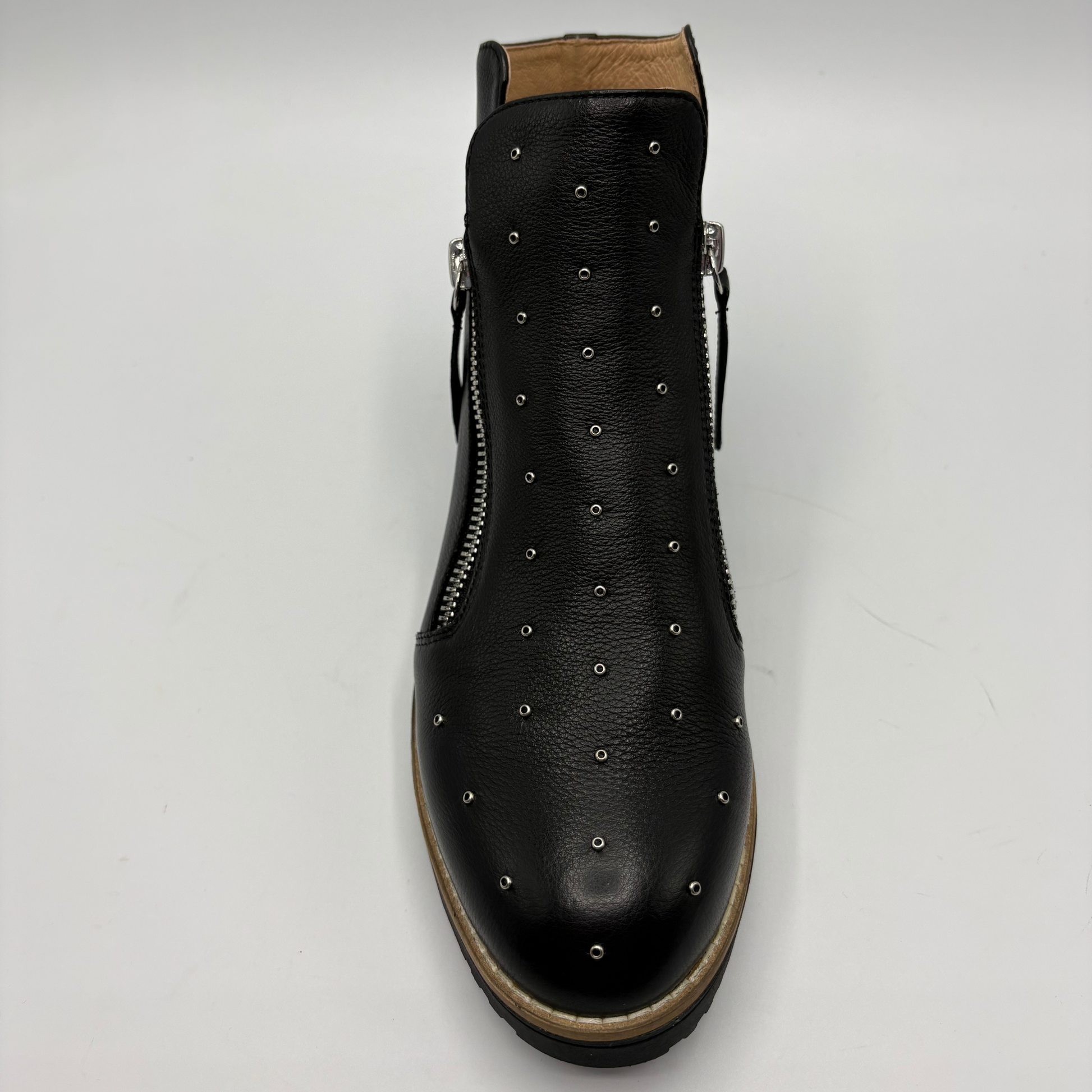 A black leather ankle boot with silver metal studs arranged in vertical rows and side zippers, shown from a top-down view on a light gray background.