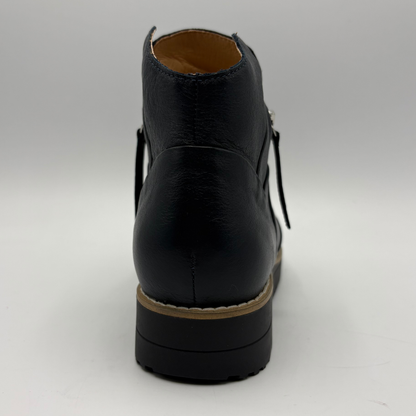 A black leather ankle boot shown from the back, featuring a chunky black sole with a tan midsole stripe and a tan interior lining, set against a plain light gray background.