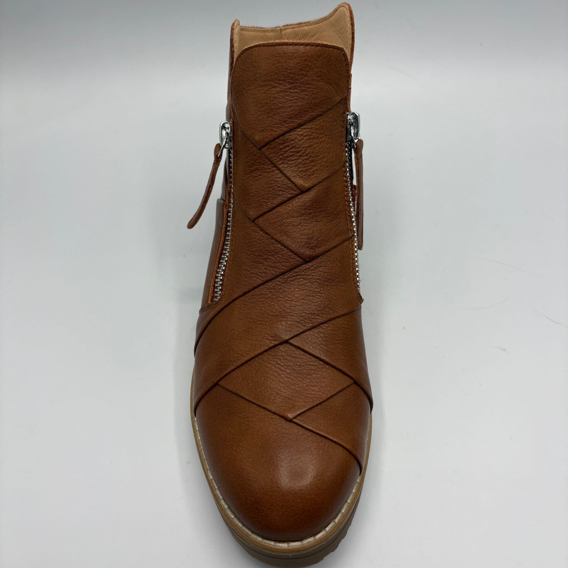 A single brown leather ankle boot with diagonal woven-style cutouts across the front and silver side zippers, shown against a plain light gray background.