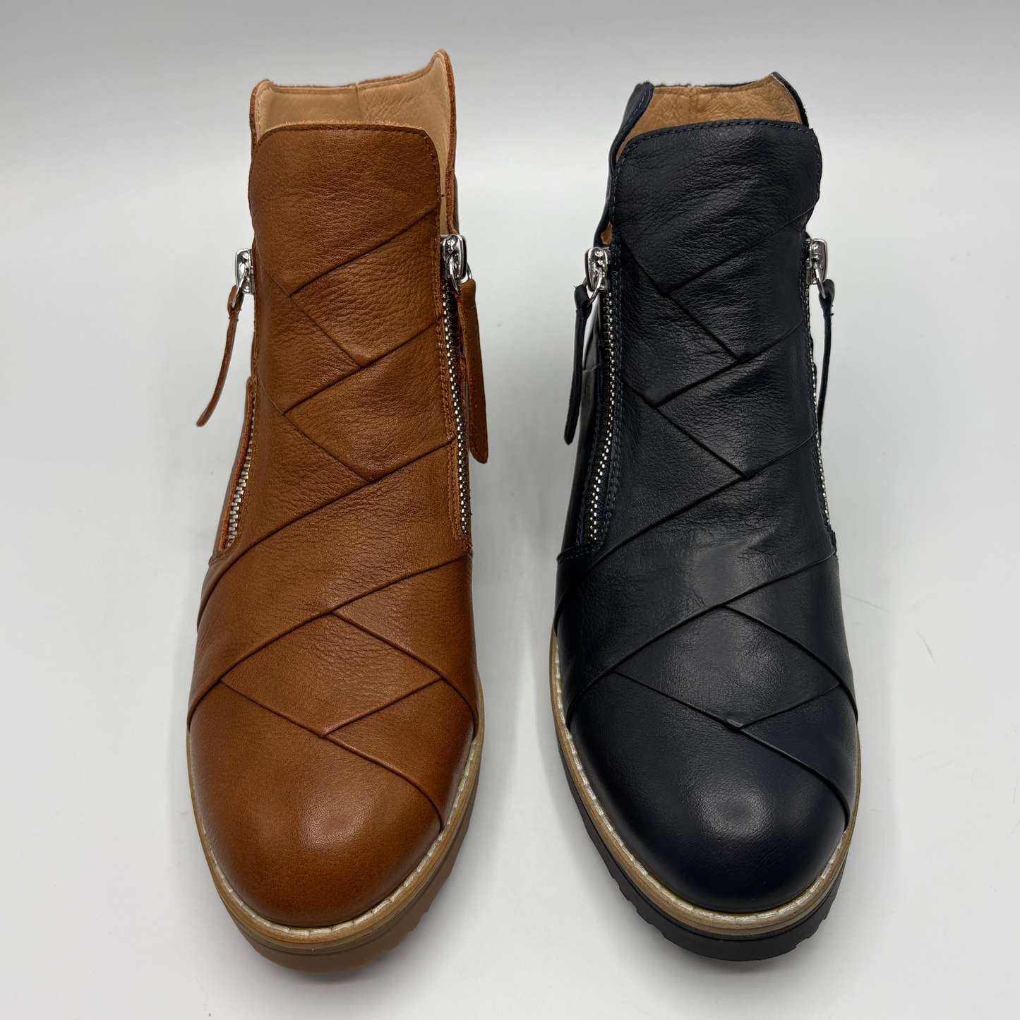 Two ankle boots with braided leather detailing, shown side by side on a light gray background. The boot on the left is tan brown, and the boot on the right is black.