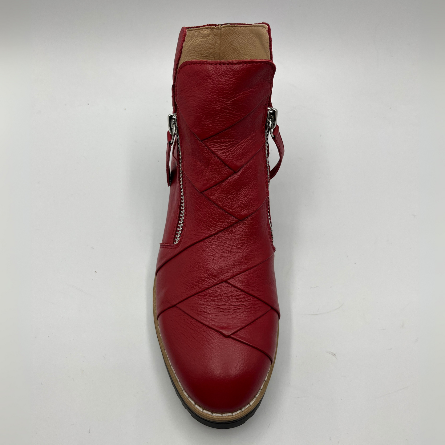 Red leather ankle boot with a braided design on a white background