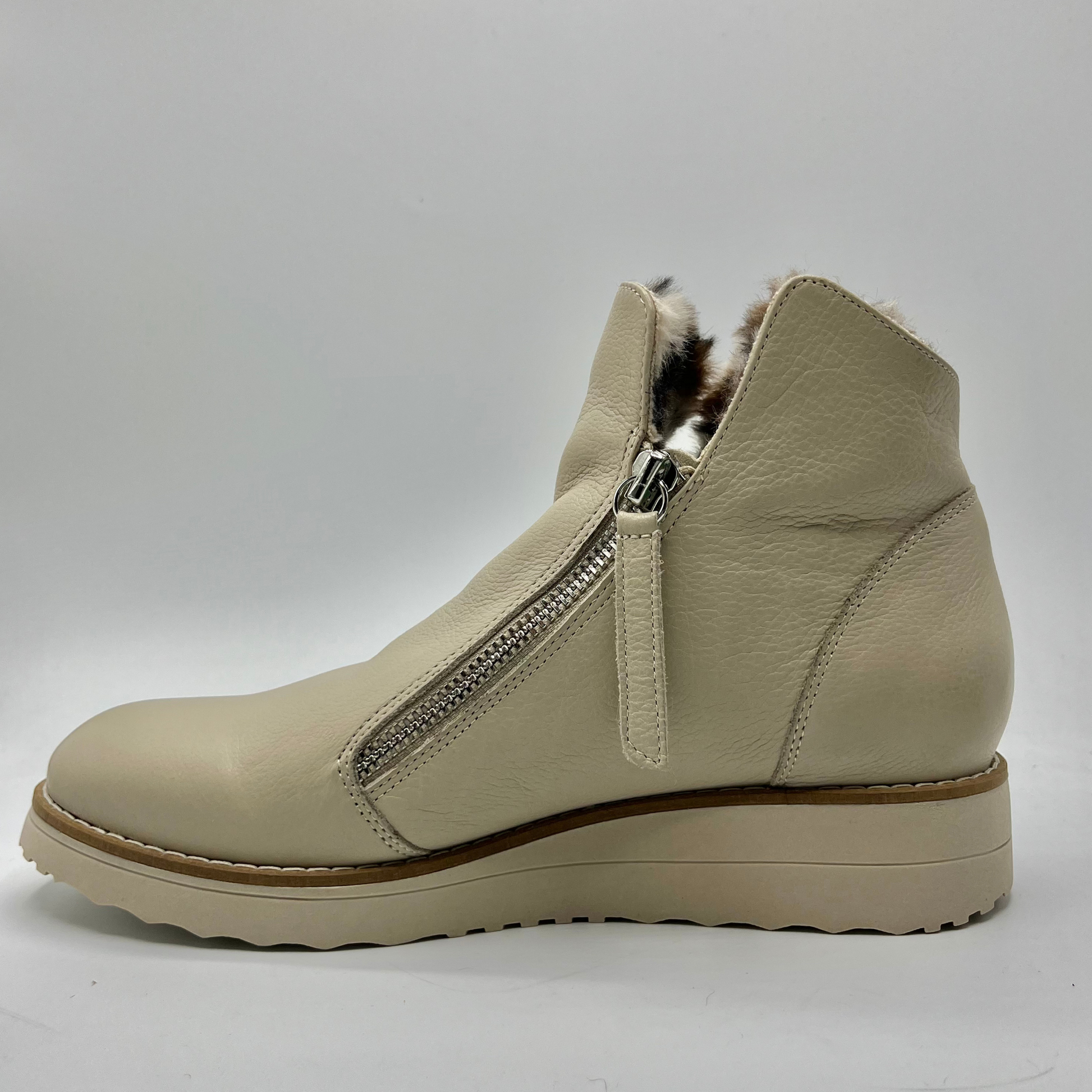 Beige ankle boot with faux fur lining and zipper on a white background