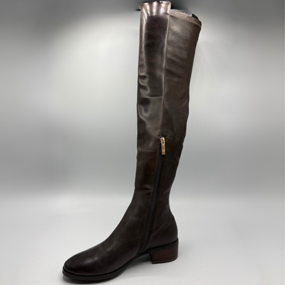 A dark brown leather over-the-knee boot with a side zipper and a small gold pull tab, shown against a gray studio background.