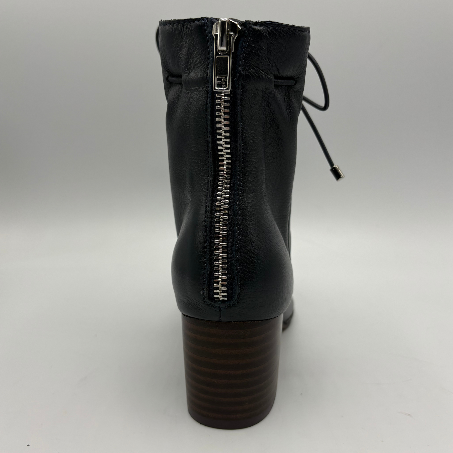 Navy leather ankle boot with a side zipper and a dark brown stacked block heel, shown from the back on a light gray background.