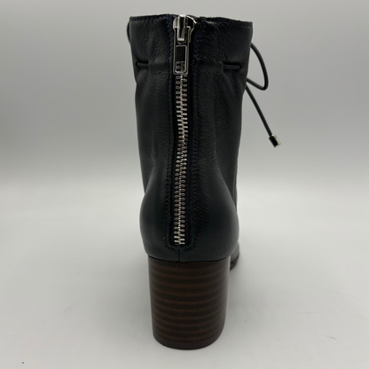 Navy leather ankle boot with a side zipper and a dark brown stacked block heel, shown from the back on a light gray background.