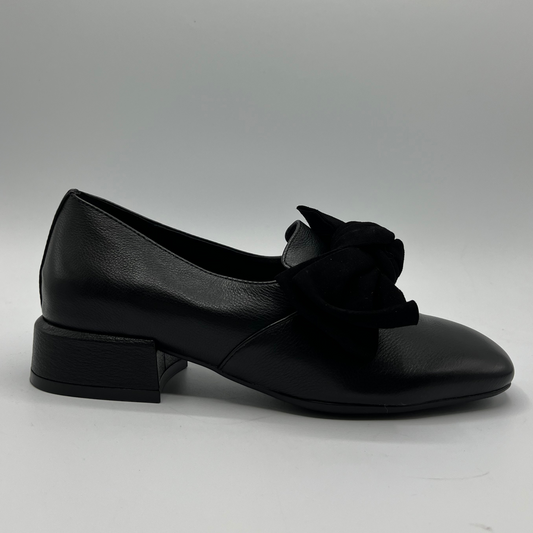 Black leather shoe with a bow on a gray background