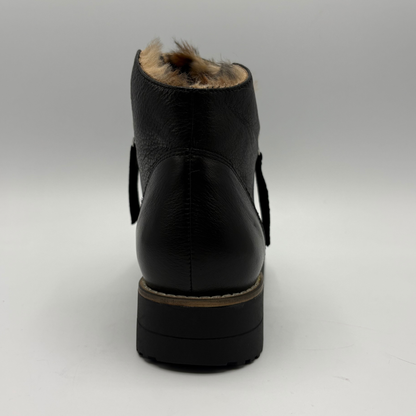 Black leather ankle boot with a low block heel, decorative side straps, and a brown faux-fur lining visible at the top, shown from the back on a light gray background.