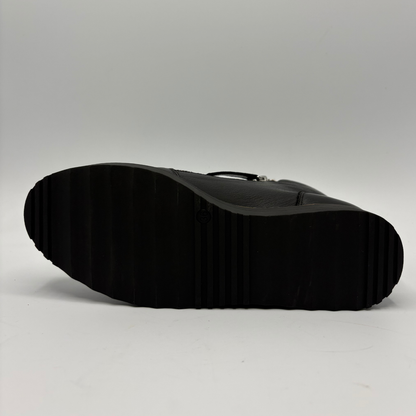 The black textured rubber sole of a boot or shoe, photographed from underneath against a neutral light gray background.