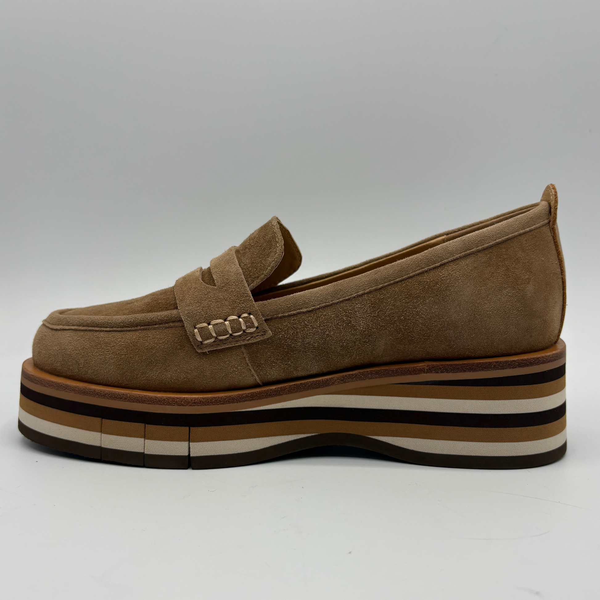 A single brown suede platform loafer with a chunky striped sole, shown in a side profile view against a neutral gray background.
