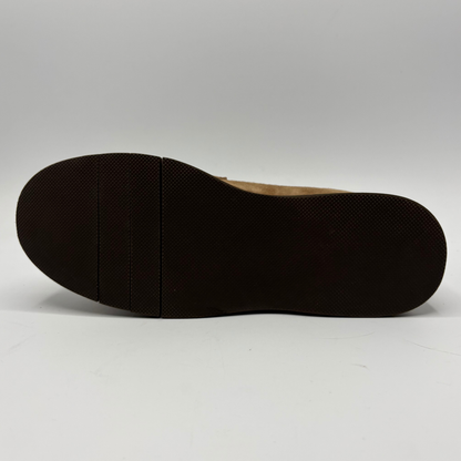 The bottom sole of a dark brown shoe, showing a textured tread pattern and a light tan inner lining, photographed against a neutral gray background.