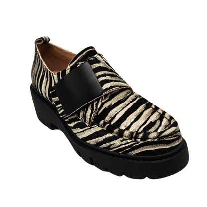 45 degree angled view of leather zebra print loafer. Velcro strap, pull on heel tab, rounded toe and leather lining.