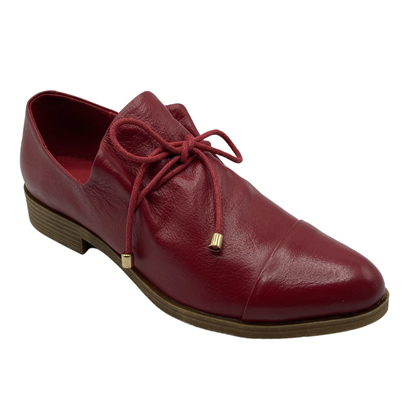 45 degree angled view of red leather shoe with red laces. Laces have shiny gold aglets.