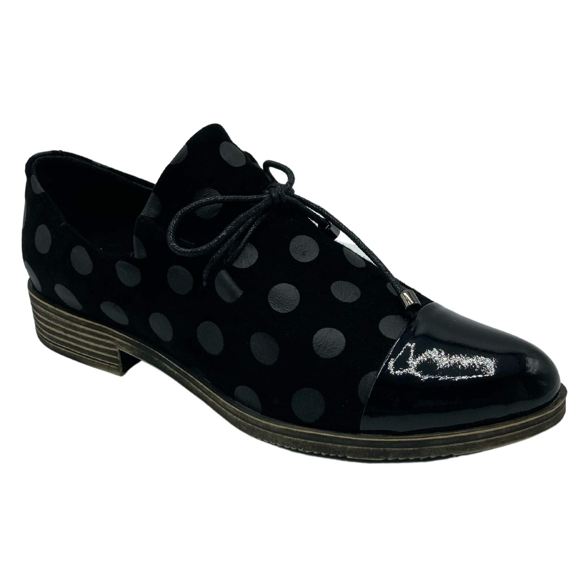 45 degree angled view of black leather shoe with black polka dots and shiny black toe cap.