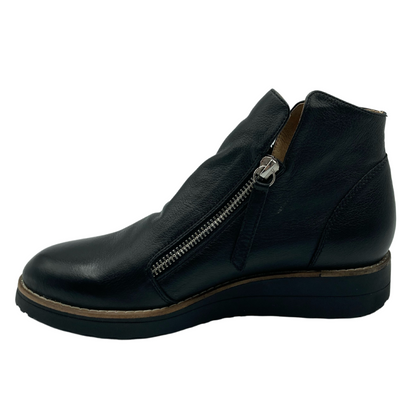 Left facing profile view of a short black leather boot with black rubber sole and silver zipper closure on the side