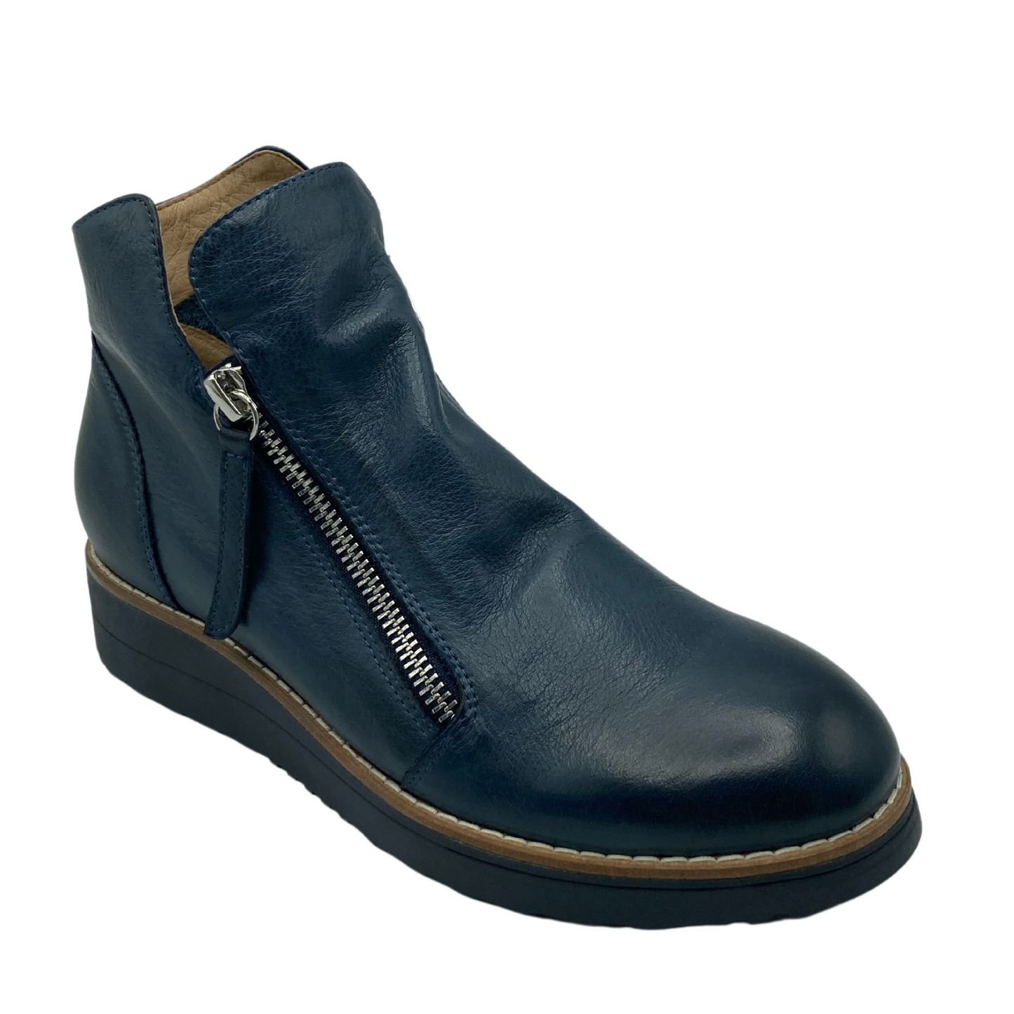 45 degree angled view of a short navy coloured leather boot with silver zipper and black rubber sole