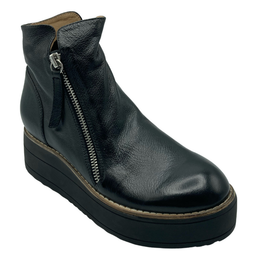 45 degree angled view of black leather wedge boot with silver zipper