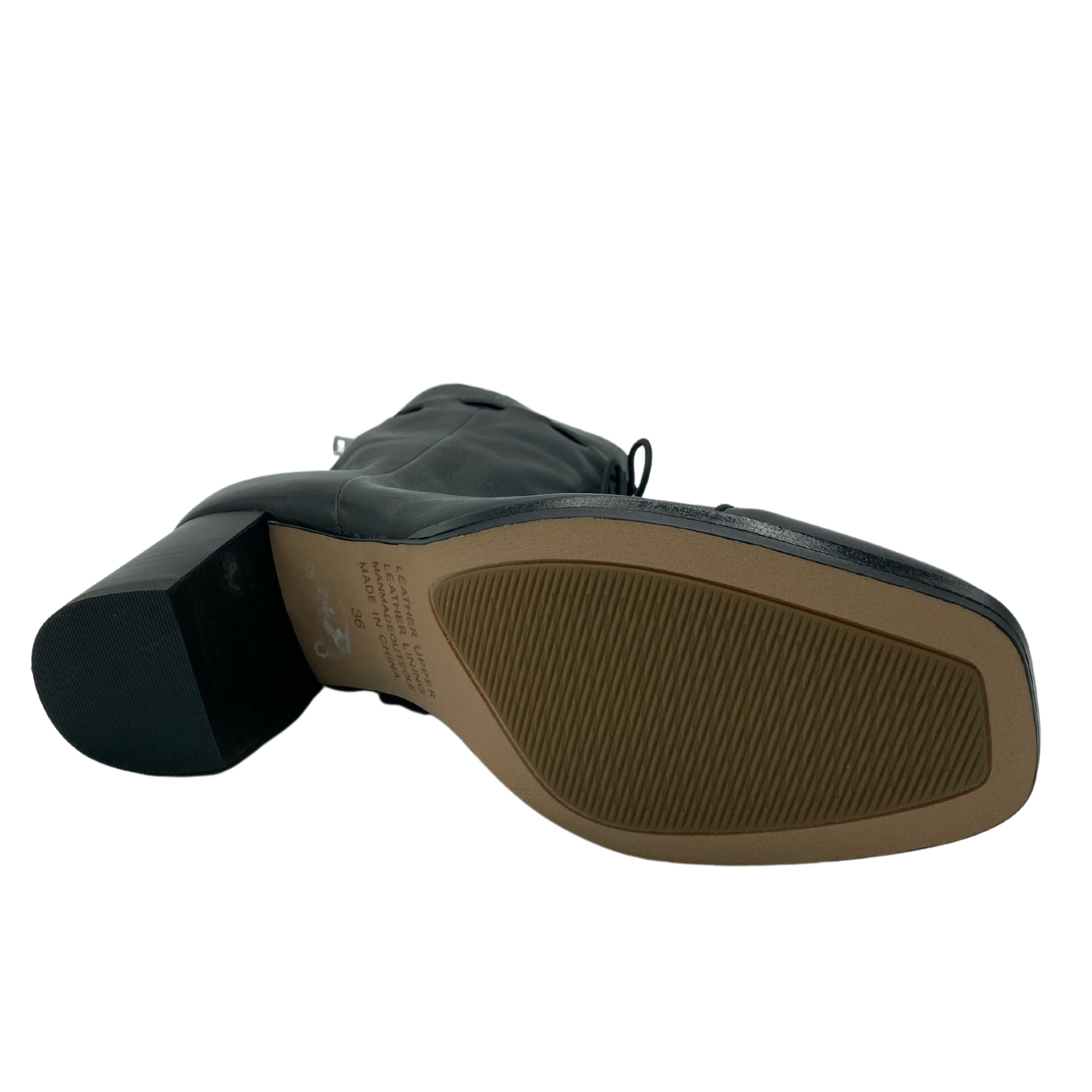 View of the bottom of black leather boot with black block heel and light brown sole