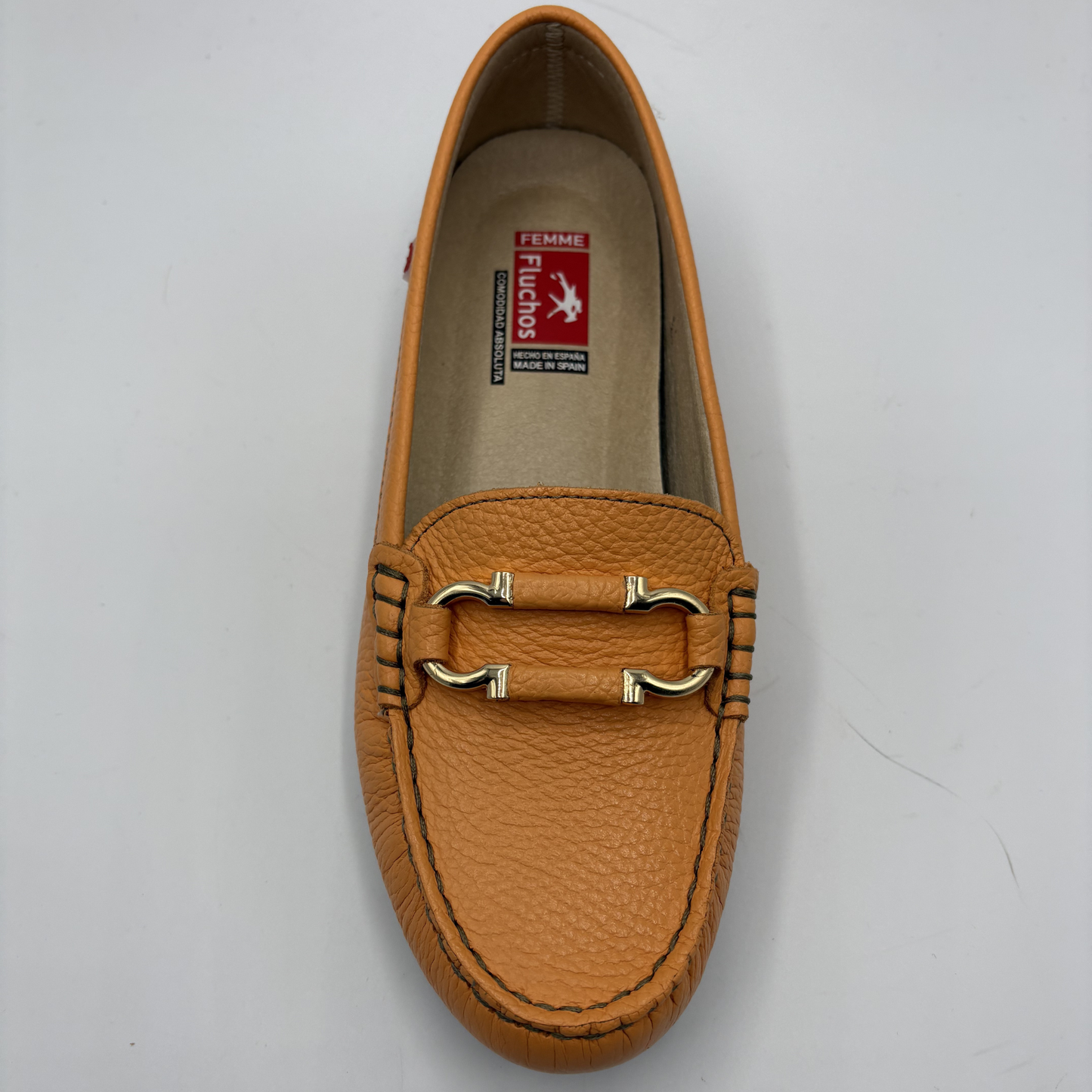 Brown loafer shoe with gold buckle on a light gray background