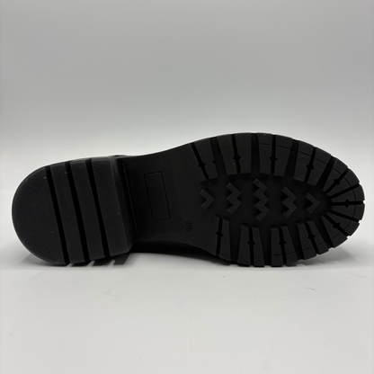 A close-up view of a black rubber boot sole, showing the tread pattern and heel structure, photographed against a neutral light gray background.