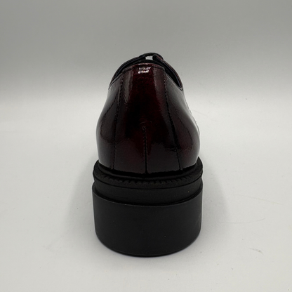 A glossy dark burgundy patent leather oxford shoe shown from the back, featuring a chunky black platform sole.