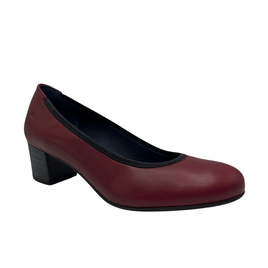 45 degree angled view of red leather pump with rounded toe and dark stacked heel