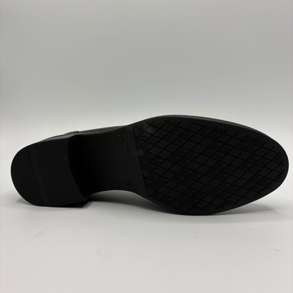 The black rubber outsole of a dress shoe, showing a textured diamond-pattern tread and a low block heel, photographed against a neutral light gray background.