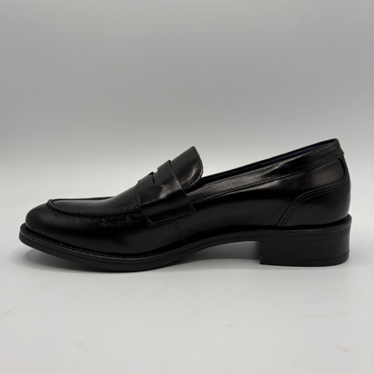 A single black leather penny loafer with a low block heel, shown in a side profile view against a neutral gray background.