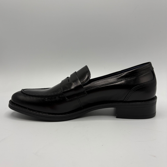 A single black leather penny loafer with a low block heel, shown in a side profile view against a neutral gray background.