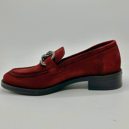 Red loafer shoe with a silver buckle on a white background