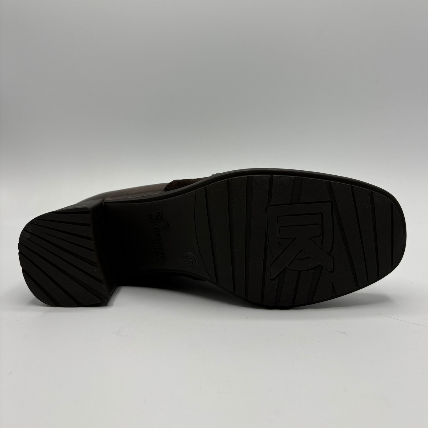 A close-up shot of the black rubber outsole of a brown leather shoe, showing the tread pattern and embossed logo on a light gray background.