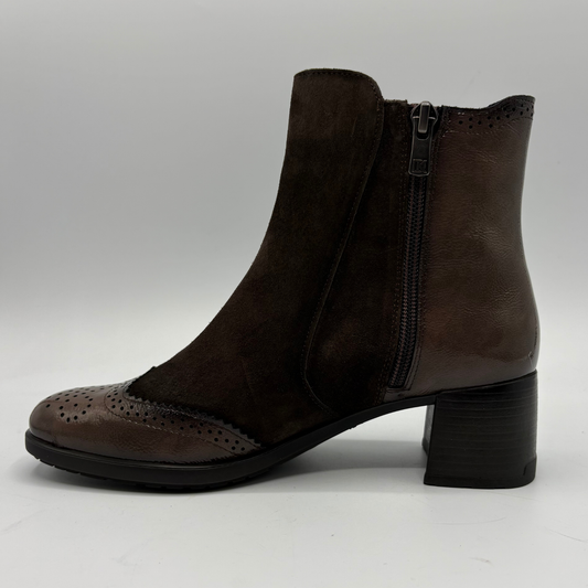 A dark brown ankle boot with a mix of suede and smooth leather panels, featuring a side zipper, perforated brogue detailing on the toe, and a chunky black block heel, shown against a neutral gray background.