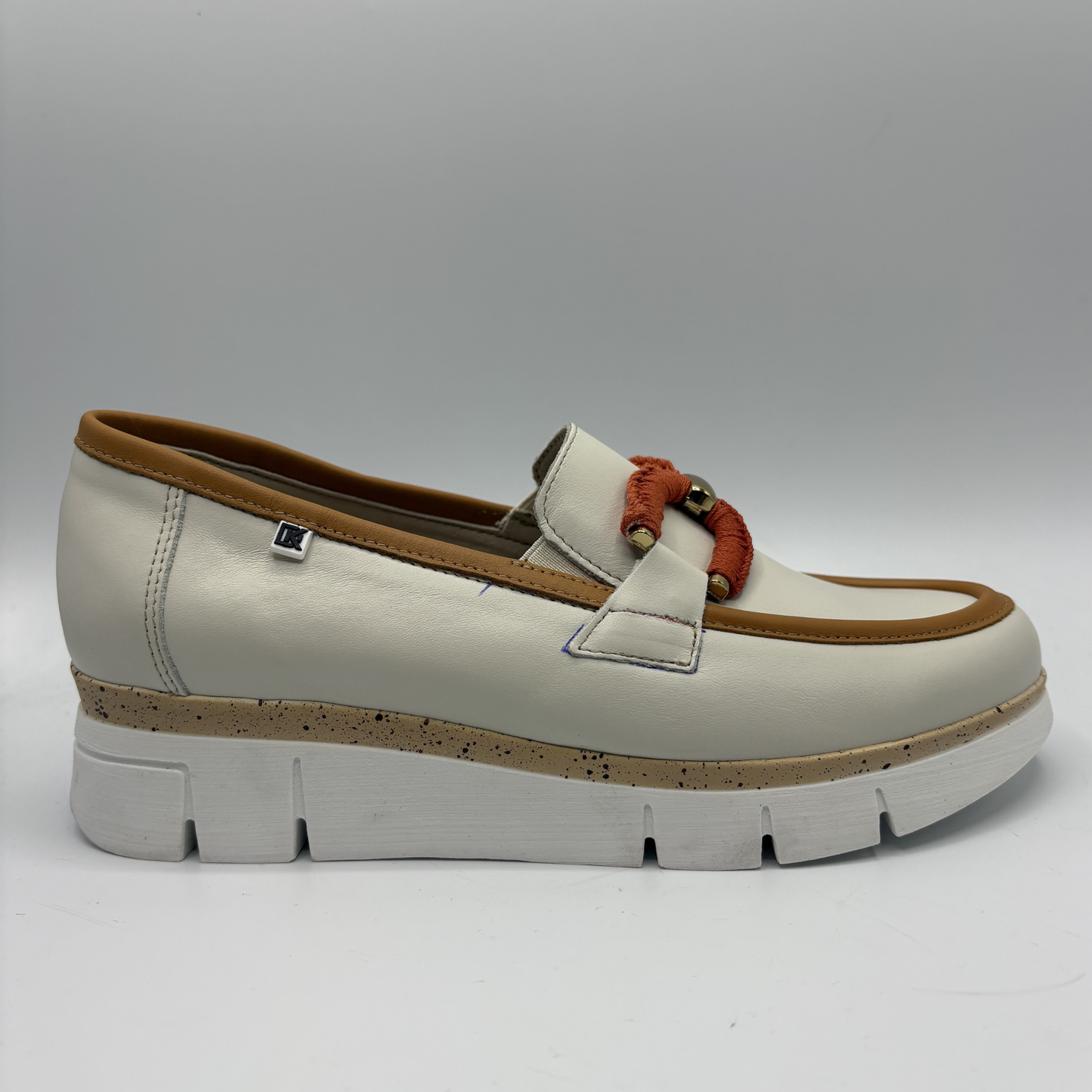 White loafer shoe with brown accents on a gray background