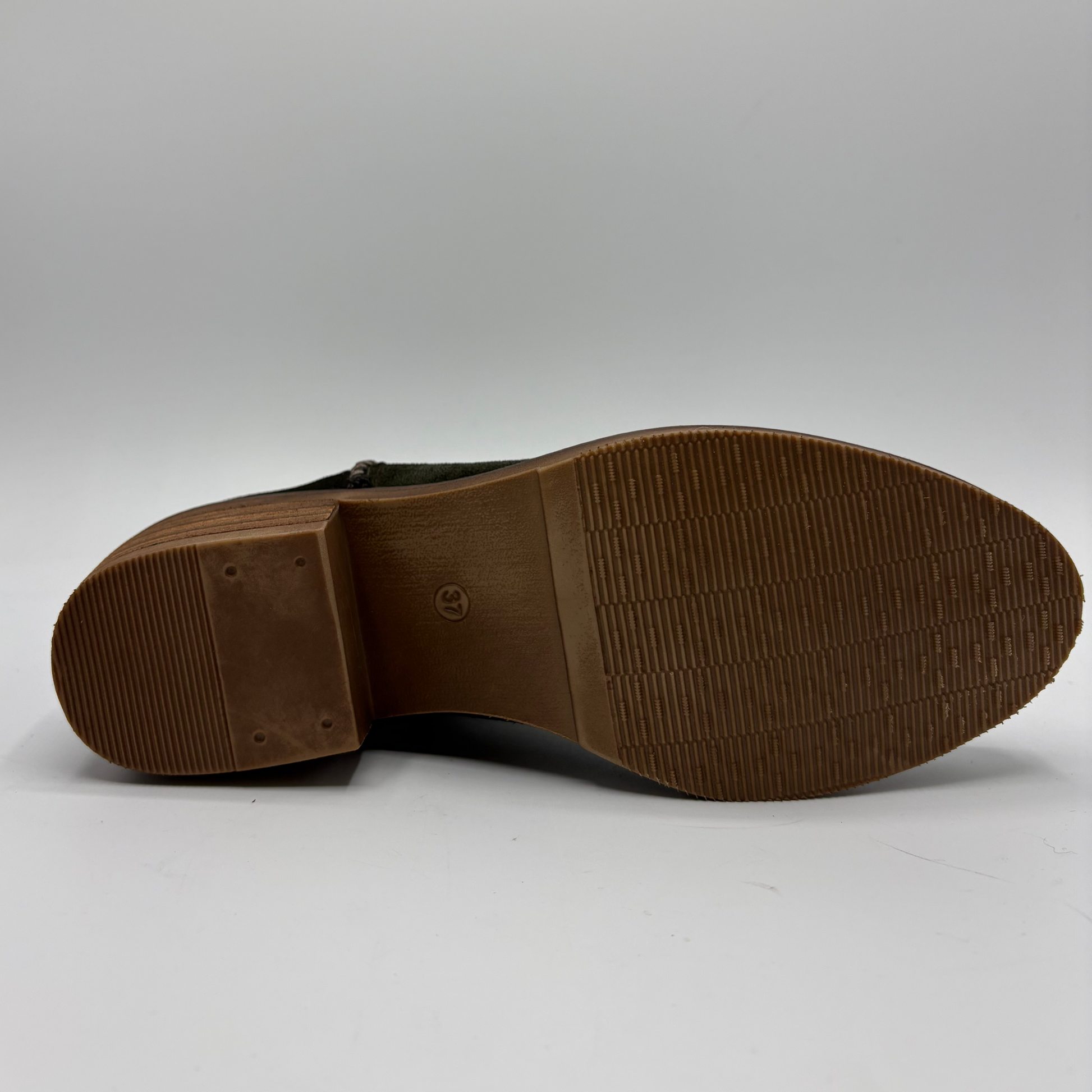 The outsole of a leather boot, showing a textured brown rubber tread and a small embossed logo in the center, photographed on a light gray background.