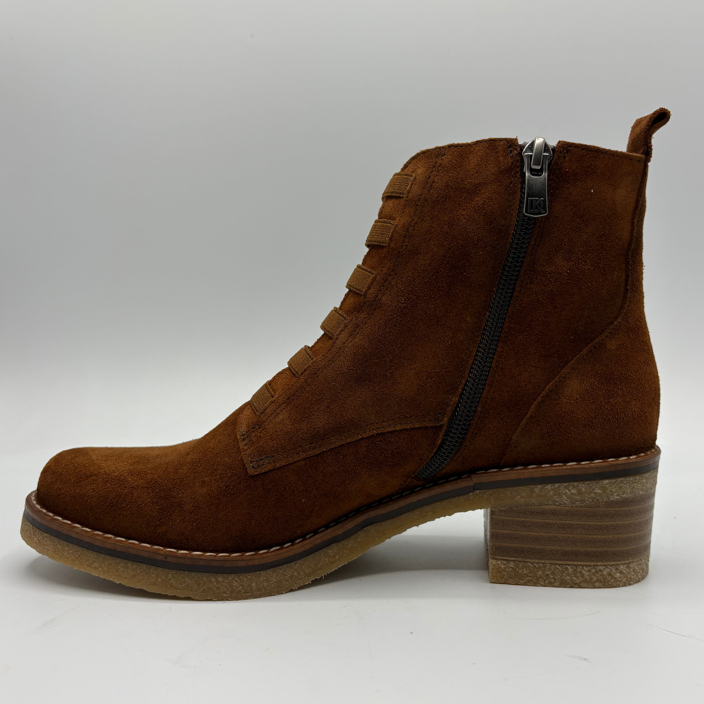 A brown suede ankle boot with a side zipper, lace-up front, and stacked block heel, shown in profile against a light gray background.