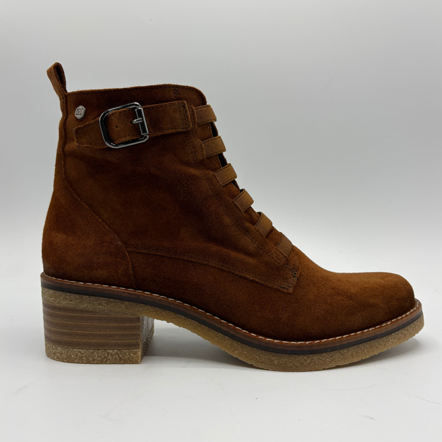 A brown suede ankle boot with a stacked block heel, lace-up front, and a decorative buckle strap on the side, shown against a light gray background.