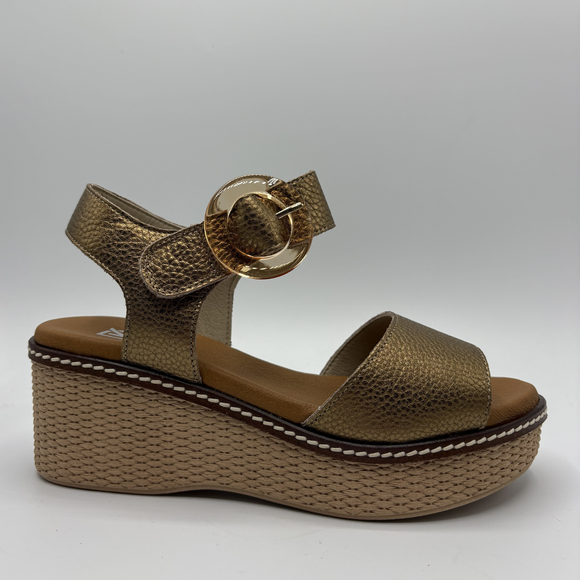 Bronze wedge sandal with a strap and buckle on a light gray background