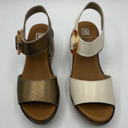 Pair of open-toe sandals with metallic gold and beige straps on a white background