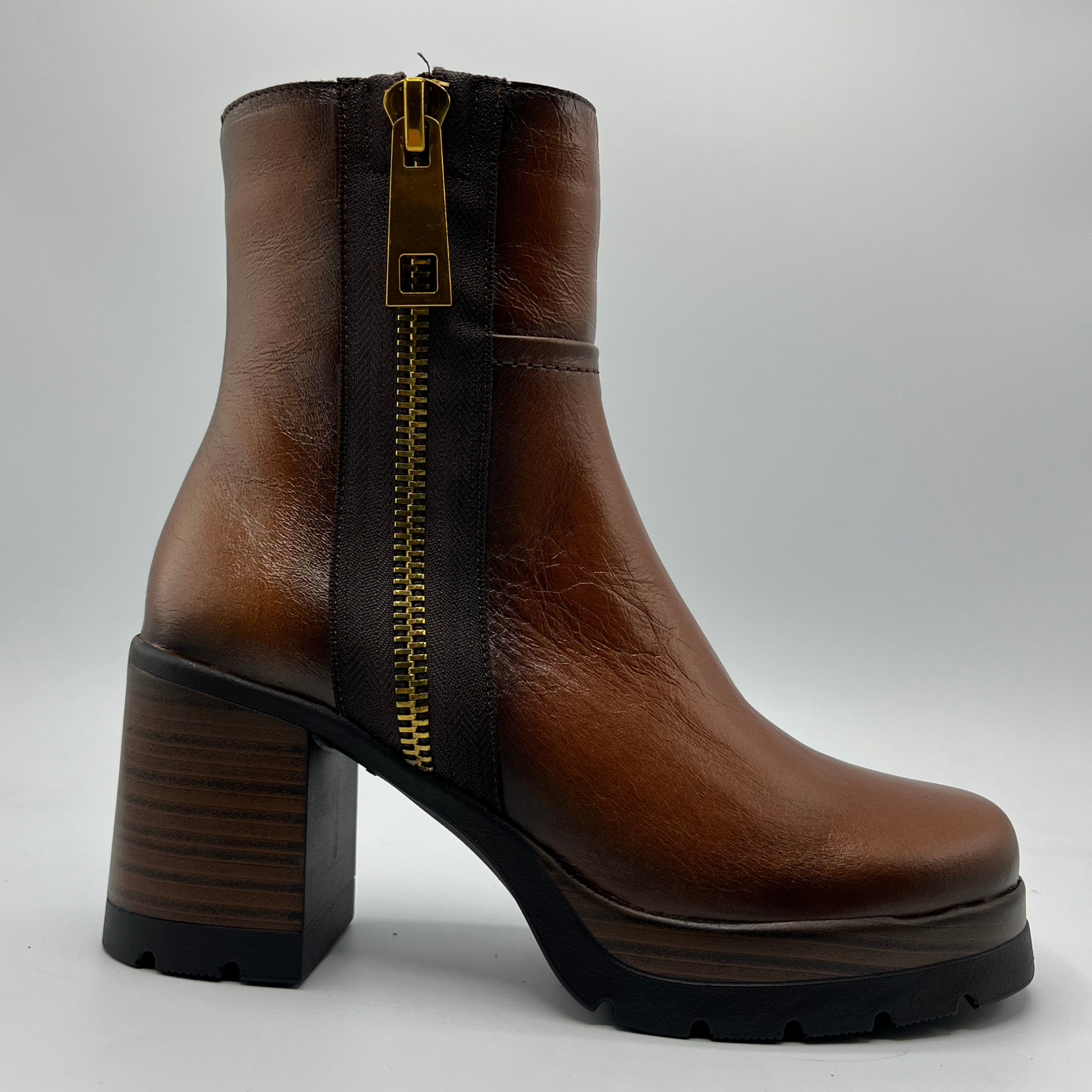 Brown leather boot with a gold zipper on a white background