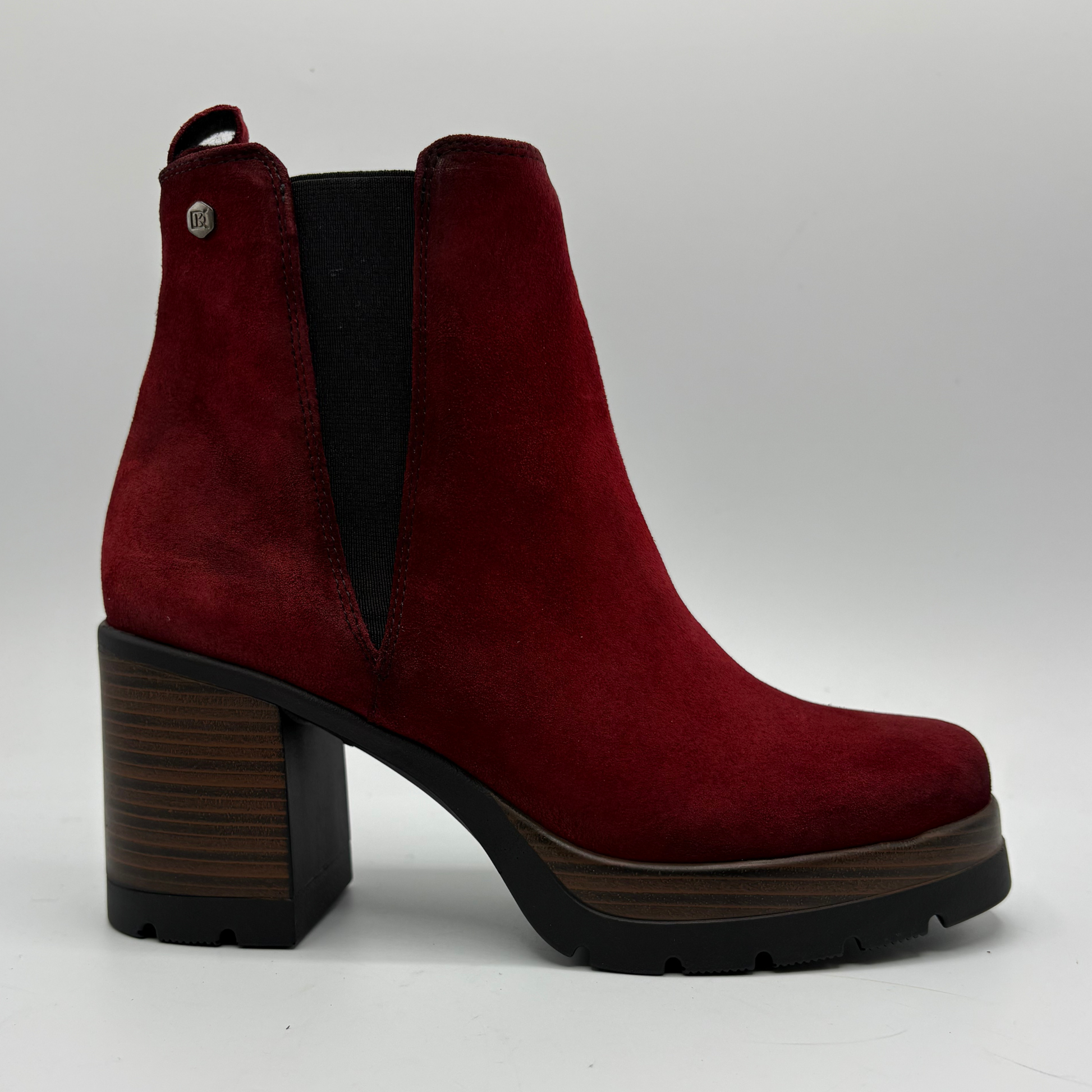 A single red suede ankle boot with a chunky block heel, black elastic side gore, and a dark wood-grain patterned heel and platform sole, shown against a light gray background.