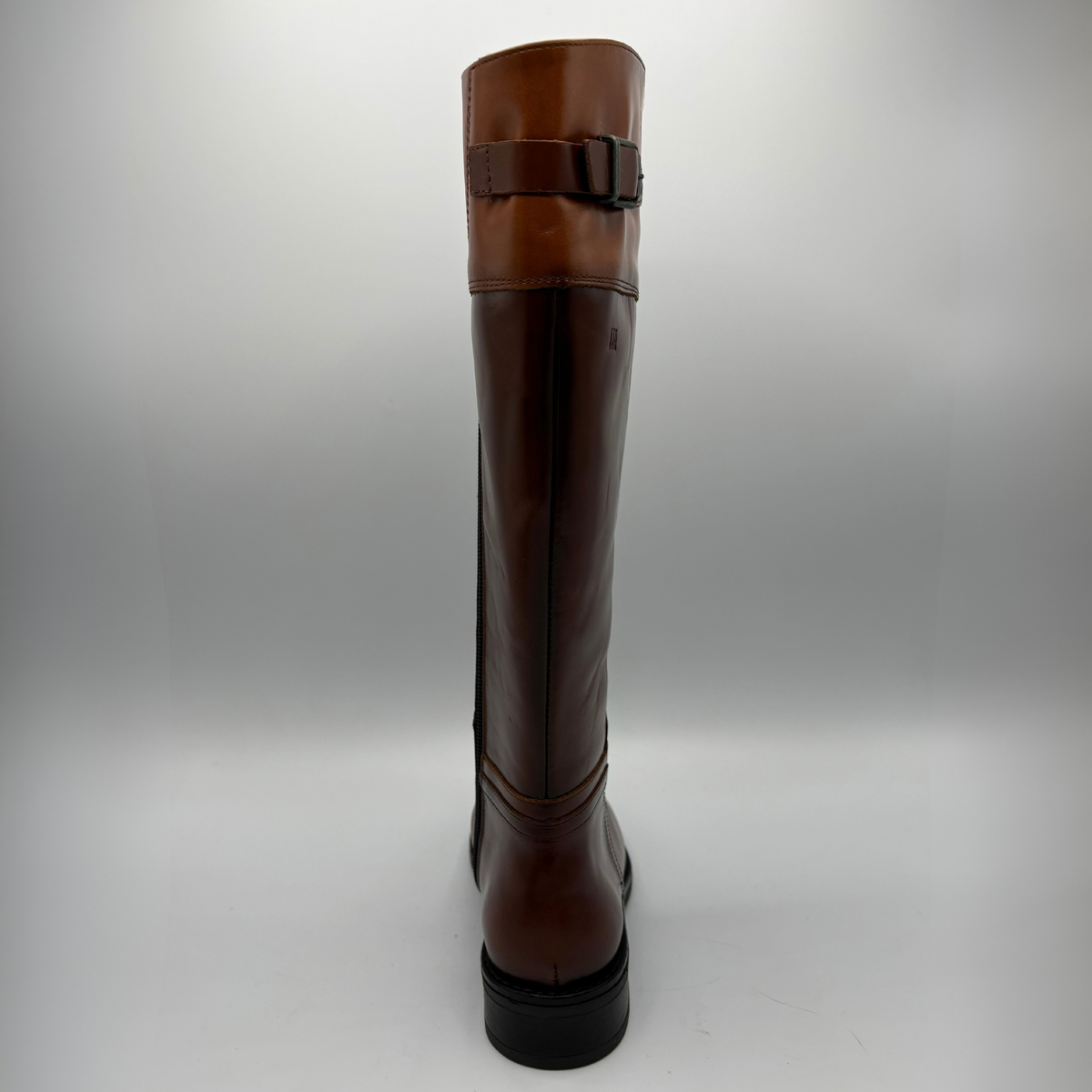 Back view of a tall brown leather boot with a decorative buckle and low black heel