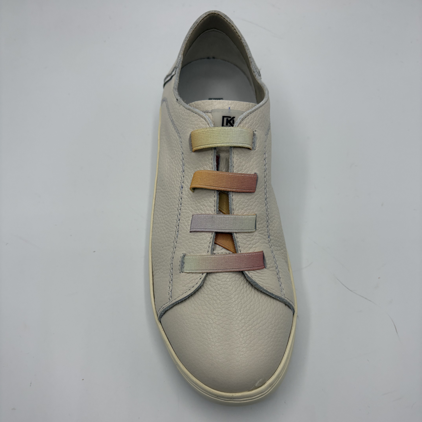 Beige sneaker with multicolored laces on a light gray background