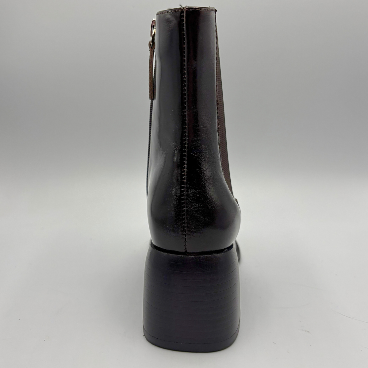 Back view of a dark brown short boot with an elastic side panel and a block heel