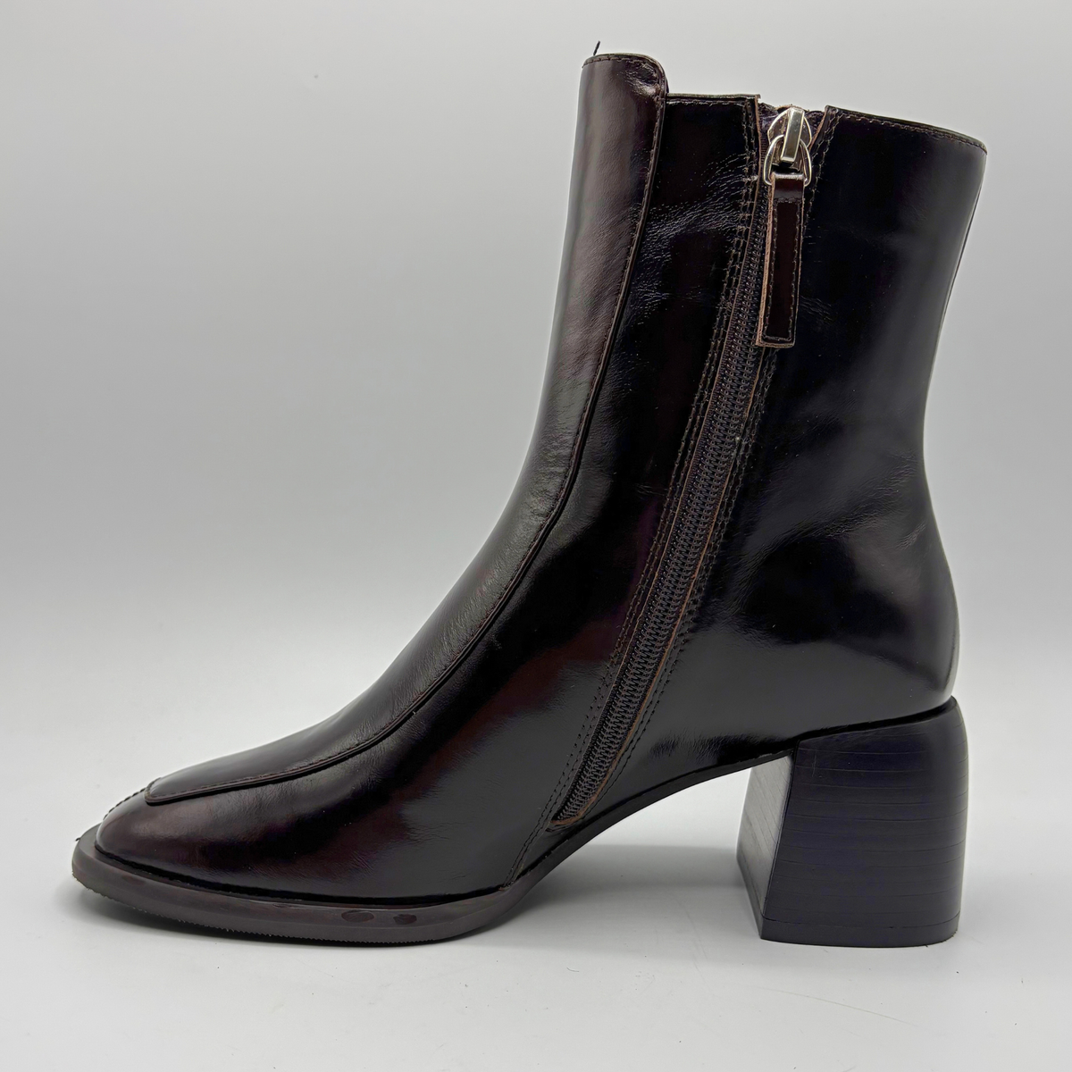 Left facing view of a dark brown short boot with an elastic side panel and a block heel