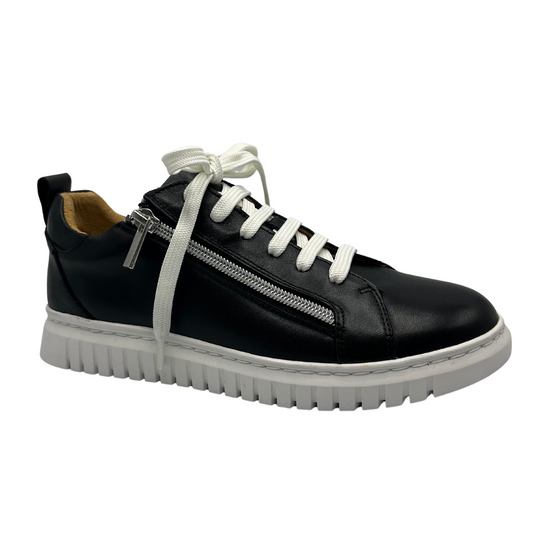 45 degree angled view of black leather sneaker with white laces, double side zipper closures and white rubber outsole.