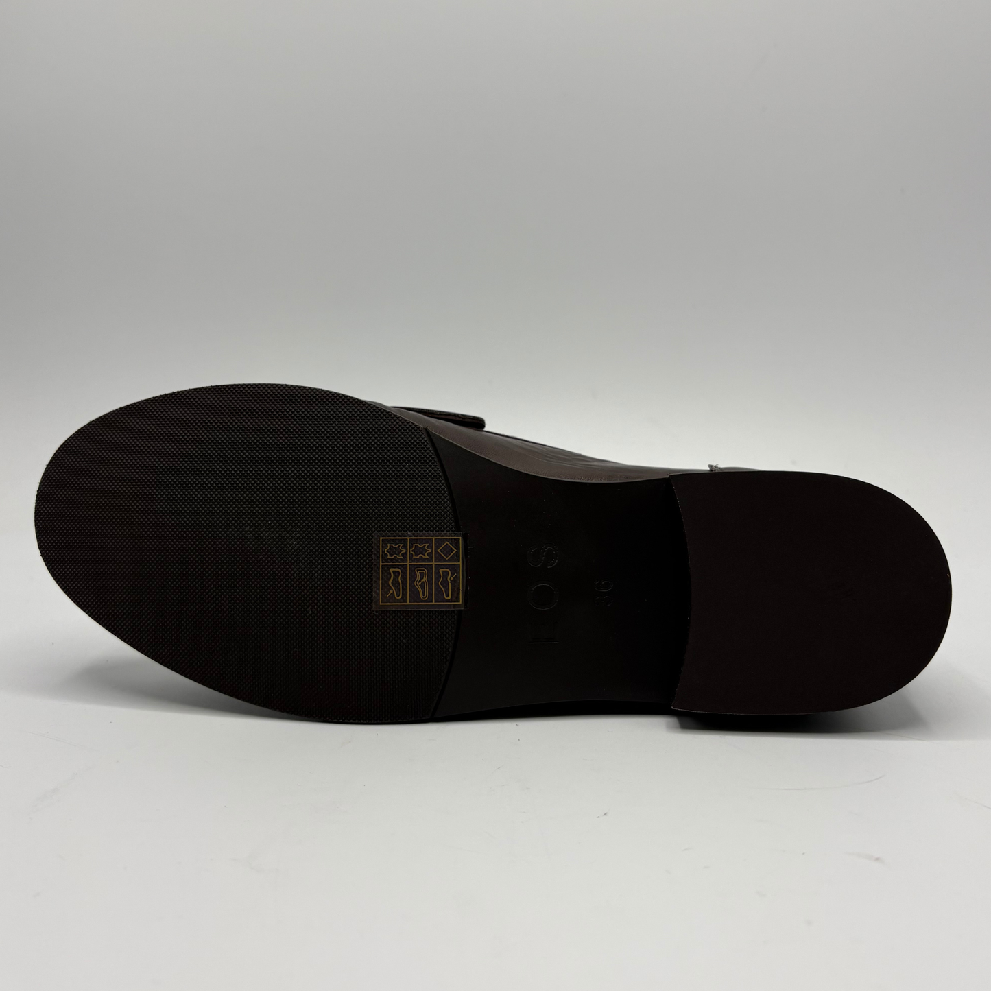 A close-up shot of the dark brown outsole of a leather shoe, set against a plain light gray background.