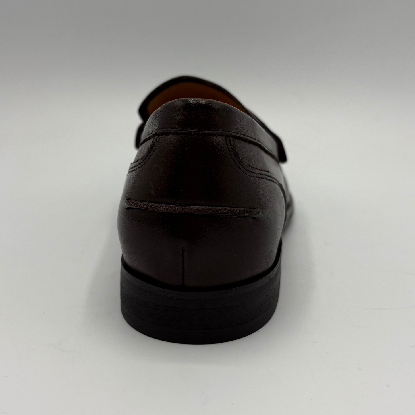 A dark brown leather loafer shown from a rear three-quarter angle on a light gray studio background.