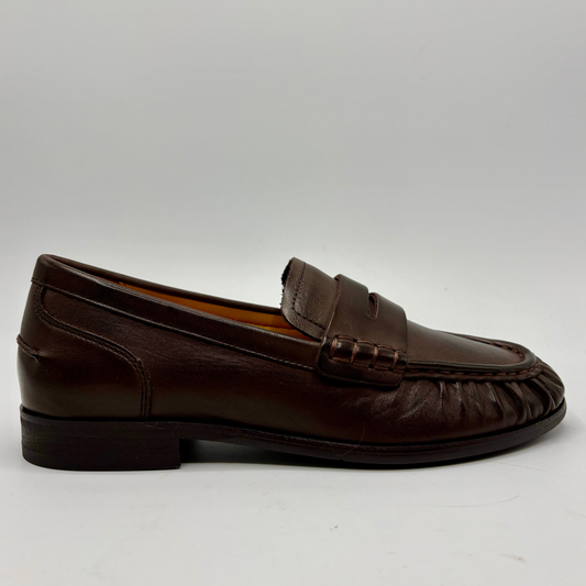 A single dark brown leather penny loafer shown in profile against a light gray background.