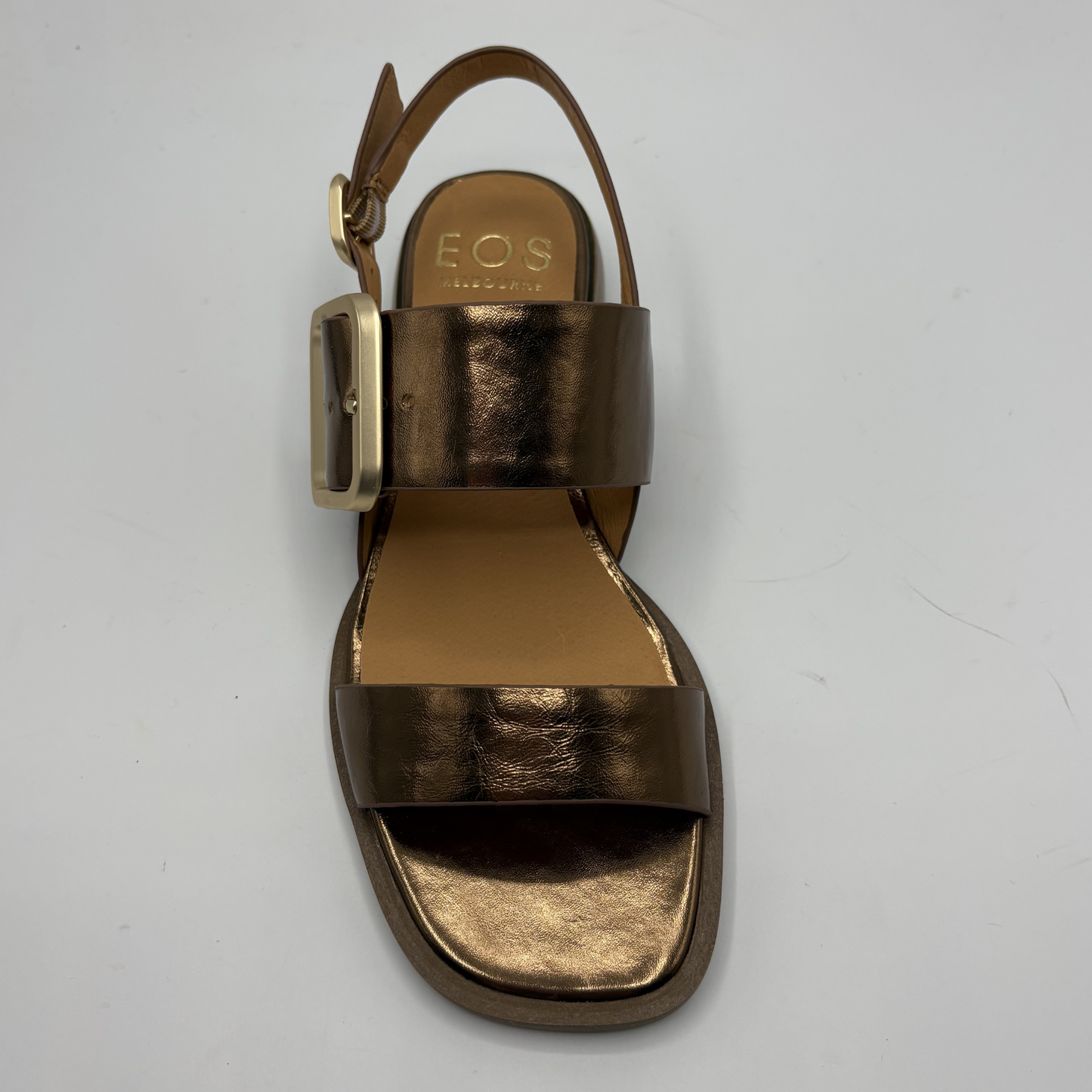 Gold sandal with a strap on a gray background