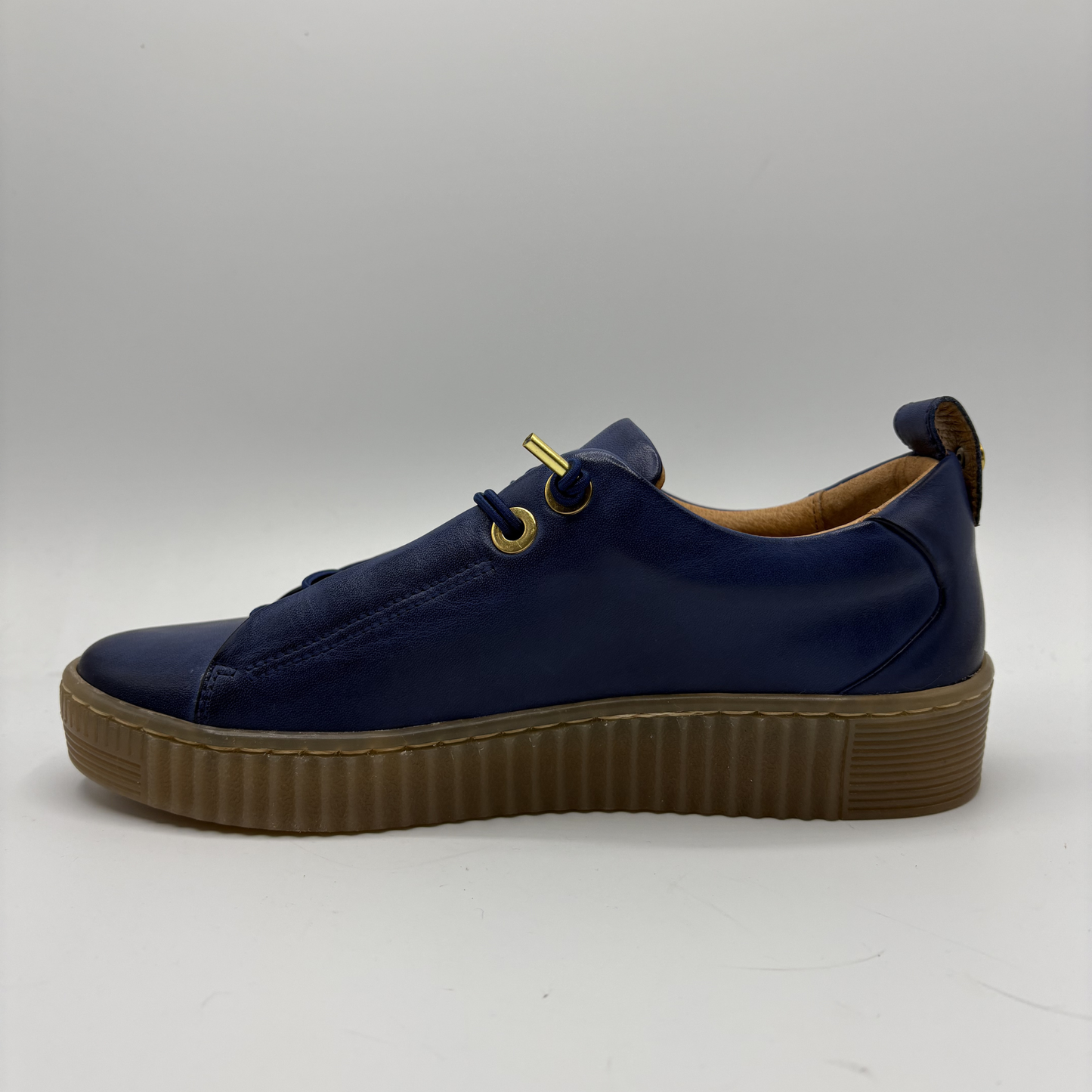 Navy blue sneaker with a brown sole on a light gray background