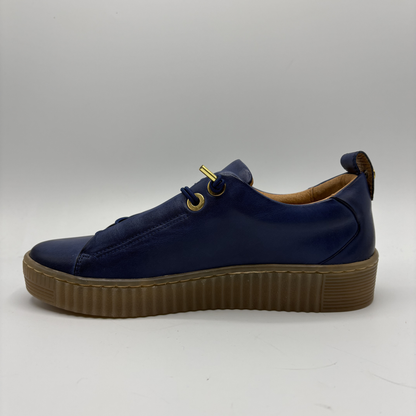 Navy blue sneaker with a brown sole on a light gray background
